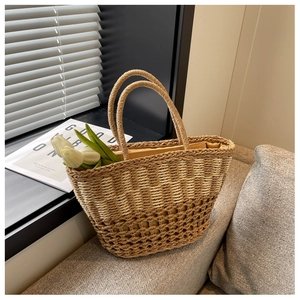 Detail of woven straw tote bag with dual-tone texture and soft fabric lining