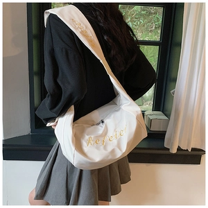 Detailed view of white nylon shoulder bag with yellow kefeler embroidery and wide strap