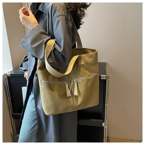 Detail of canvas tote bag showing two front zipper pockets and shoulder strap functionality