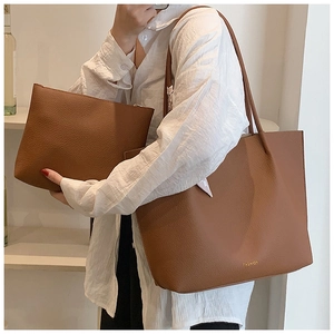 Detailed view of caramel brown leather tote bag and matching zippered pouch on model
