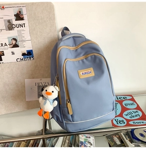 Detail of blue casual backpack with plush duck pendant and stylish front pocket