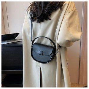 Detailed back view of a woman wearing a black leather saddle bag with silver buckle