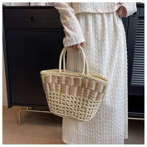 Detail of woven straw beach bag featuring beige and brown patchwork with hollow wave texture