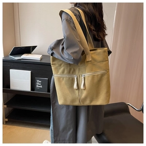 Close-up of a large khaki canvas tote bag featuring double front zipper pockets