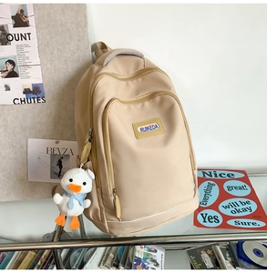 Detail of beige large capacity backpack with RUIKEDA logo and cute white duck pendant