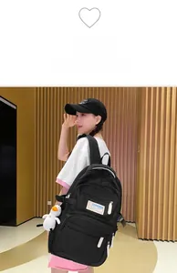 Detail of high-capacity black backpack with white zipper accents and plush duck charm