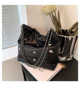 Detail of black leather bucket bag with silver metal studs and chain strap decoration