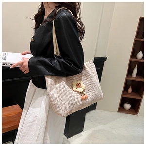 Detail of beige woven tote bag featuring yellow 3D floral accents and slender shoulder straps