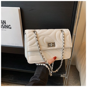 Détail du sac matelassé blanc avec fermoir rotatif argenté et bandoulière en chaîne cuir
