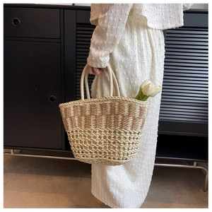 Close-up of a dual-tone woven straw beach bag with intricate mesh patterns and round handles