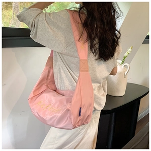 Detail of pink oxford fabric hobo bag with wide shoulder strap and floral embroidery