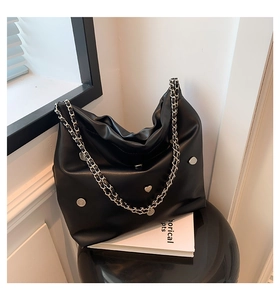 Detail of black leather bucket bag featuring silver heart rivets and chain strap