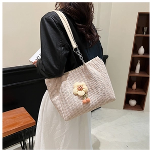 Detail of woven straw tote with 3D sunflower decor and leather chain strap