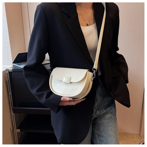 Detail of a creamy white half-moon saddle bag showing matte texture and silver hardware