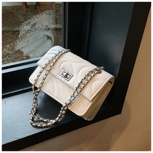 Détail du sac matelassé blanc avec surpiqûres en V et fermoir rotatif argenté élégant