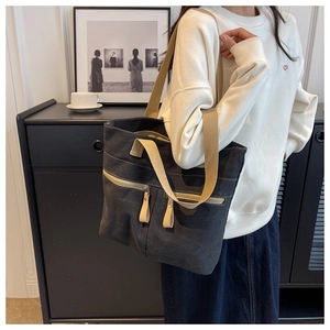 Detail showing two front zipper pockets on dark gray canvas tote bag with beige straps