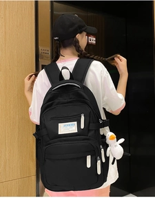 Close-up of a black casual backpack featuring a white duck pendant and brand label