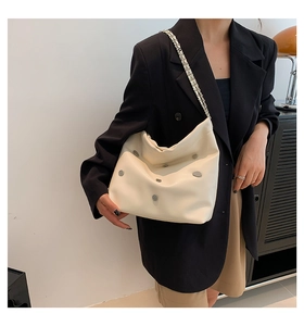 Detail of cream white leather shoulder bag with silver studs and metal chain strap