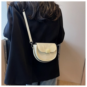 Detail view of cream white saddle bag with square buckle worn by a model
