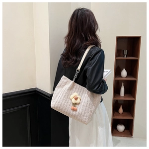 Detail of a large woven tote bag with 3D flower charm on shoulder strap for summer style