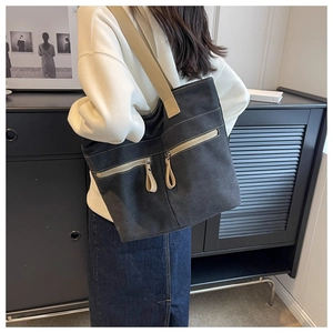Detailed side view of the black canvas tote bag worn on shoulder by a female model