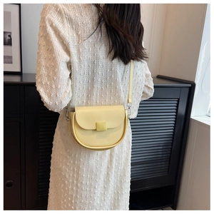 Detail of a creamy yellow half-moon saddle bag showing smooth leather and silver hardware
