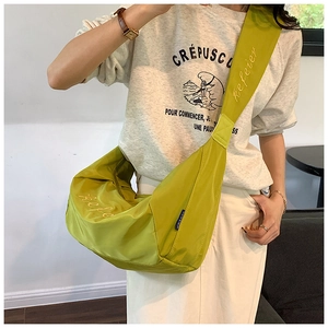 Detail of light green Oxford dumpling bag showing wide strap and brand logo embroidery