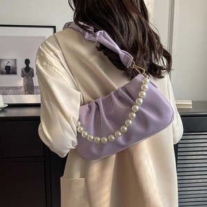 Purple pleated cloud bag with pearl chain decoration on elegant model shoulder