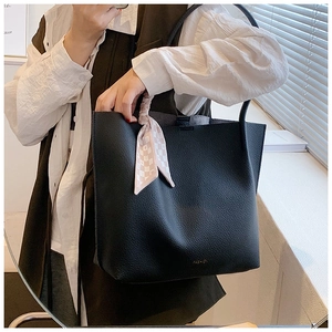 Detailed macro view of black lychee grain texture and gold FASHION logo on tote bag