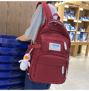 Detail view of burgundy large capacity backpack with adjustable side buckles and plush duck