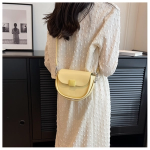Detail of light yellow saddle bag with elegant buckle shown in a stylish indoor setting
