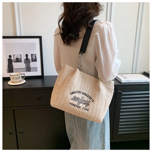 Detail of woven straw tote bag with black embroidery and leather chain shoulder strap