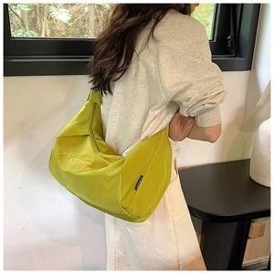Detail of lime green nylon crossbody bag showing embroidery and spacious dumpling design