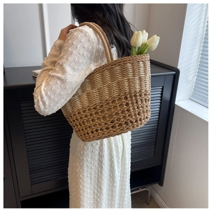 Detail of handwoven straw beach bag featuring large mesh pattern and knotted rope handles