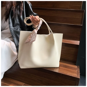 Detail of cream tote bag with lychee texture and decorative pink plaid ribbon scarf