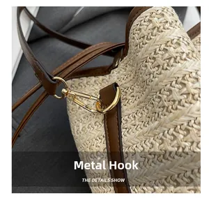 Detail of the golden metal hook and brown leather strap on the woven straw bucket bag