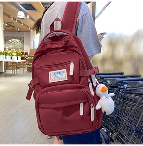 Detailed view of burgundy nylon backpack with RKD BAG label and white duck pendant