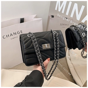 Détail du sac bandoulière en cuir matelassé noir avec chaîne en argent et fermoir rotatif