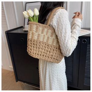 Detail of two-tone woven straw tote bag featuring contrast hollow mesh and plant fiber texture