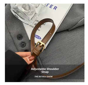 Detail of adjustable brown leather shoulder strap with gold buckle on a woven bucket bag