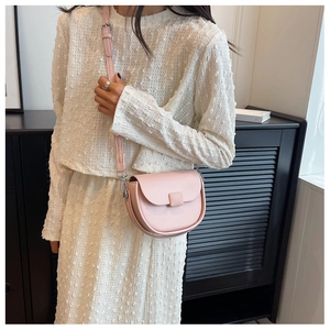 Detail of pink saddle bag with adjustable shoulder strap and matte finish on white outfit