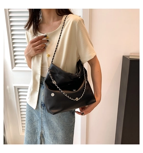 Detailed view of black soft leather tote bag featuring stylish silver chain and metal buckle
