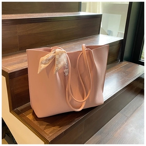 Detailed view of pink pebble grain tote bag with decorative silk scarf on wooden stairs