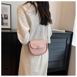 Detail of pink leather saddle bag with square buckle worn as a stylish crossbody bag