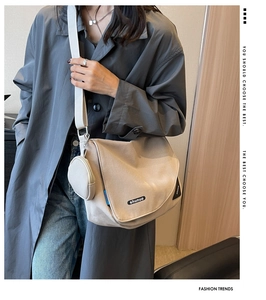 Vue détaillée d'une besace en nylon beige avec une petite pochette ronde zippée assortie