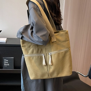 Large olive green canvas tote bag with dual front pockets and wide shoulder straps
