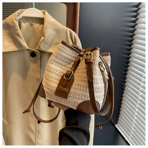 Detail of woven straw bucket bag with leather accents and golden metal square buckle