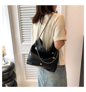 Detail view of large black bucket bag with silver heart studs and chain strap