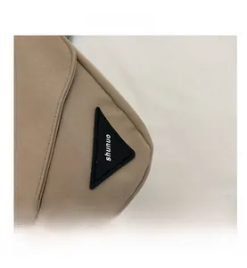 Vue détaillée de la texture en toile kaki et du logo triangulaire noir du grand sac