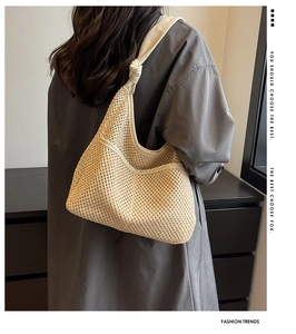 Detail of cream woven shoulder bag featuring textured mesh pattern and knotted strap accents